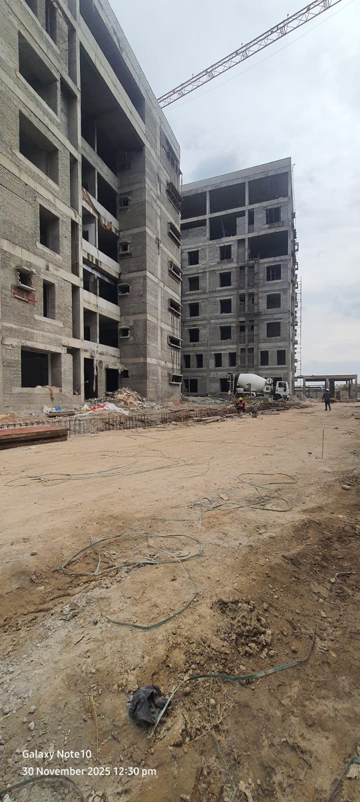 Twin multi-storey apartment blocks under construction with tower crane and transit mixer